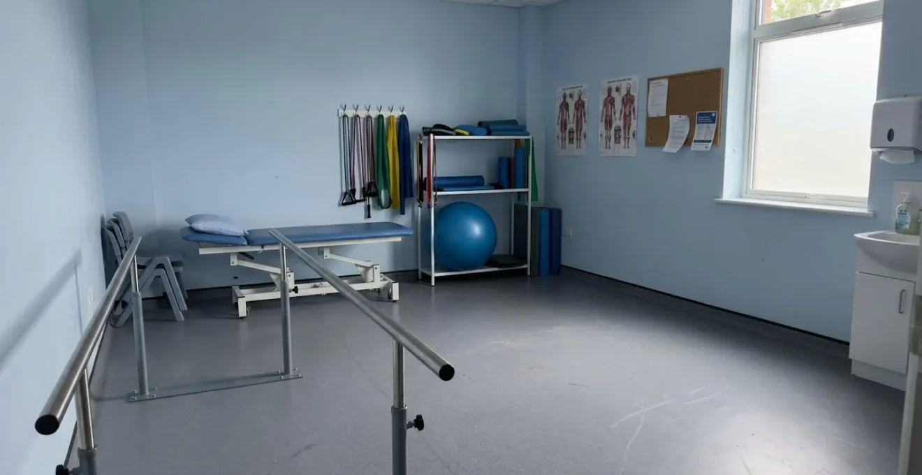 A contemporary physiotherapy room with rehabilitation equipment including parallel bars and therapy aids in natural lighting